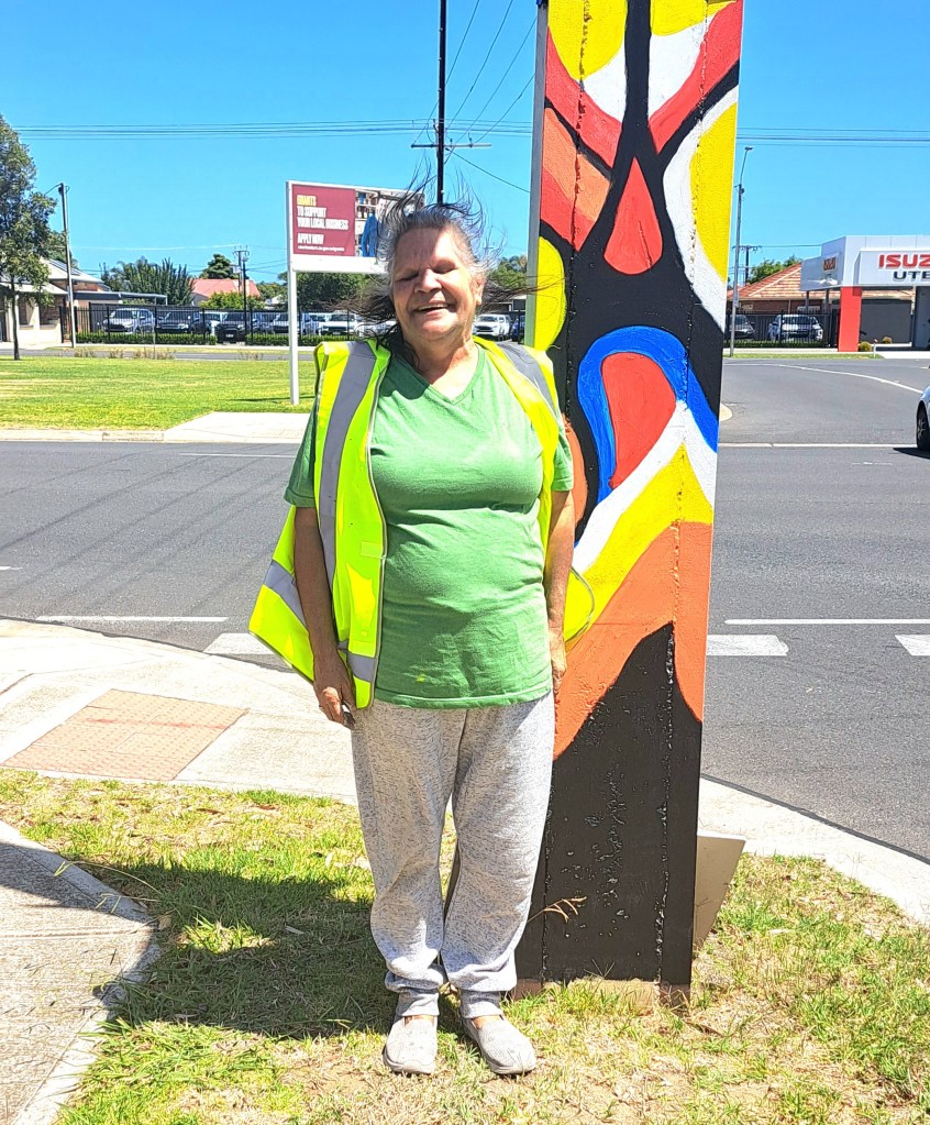 Artist Leanne Shearing stands next to the stobie pole which displays her artwork titled Tranquility Corner.